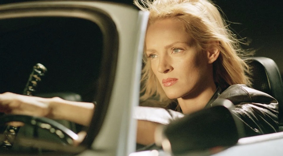 Uma Thurman as the Bride in Kill Bill, driving at night with a katana beside her